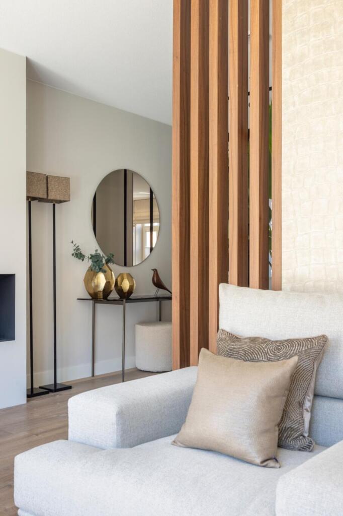 Een ronde spiegel hangend aan de muur in combinatie met een roomdivider