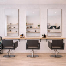 Rechthoekige verzilverde blanke spiegels aan de muur in een lichte kapperszaak