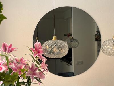 Ronde gekleurde spiegel aan de muur